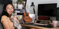 Chat à côté d'une guitare dans les bras de sa maîtresse