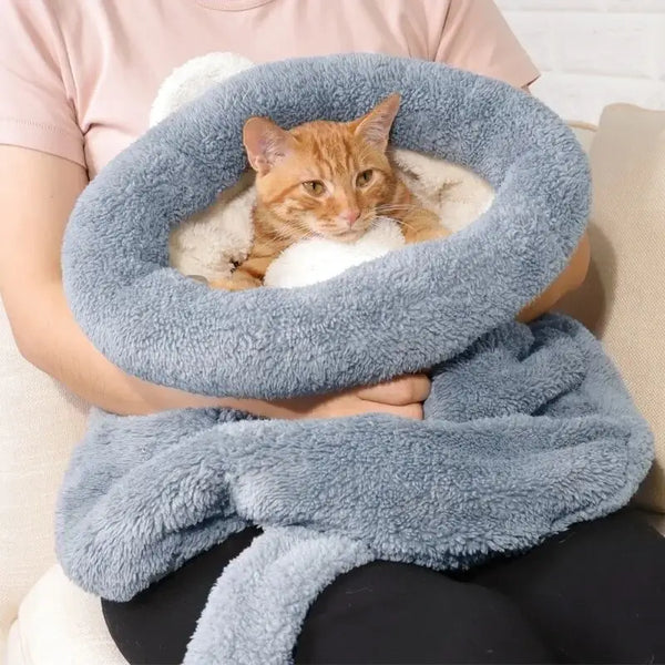 Chat en position assise dans son cocon pour chat sur les genoux de sa maîtresse