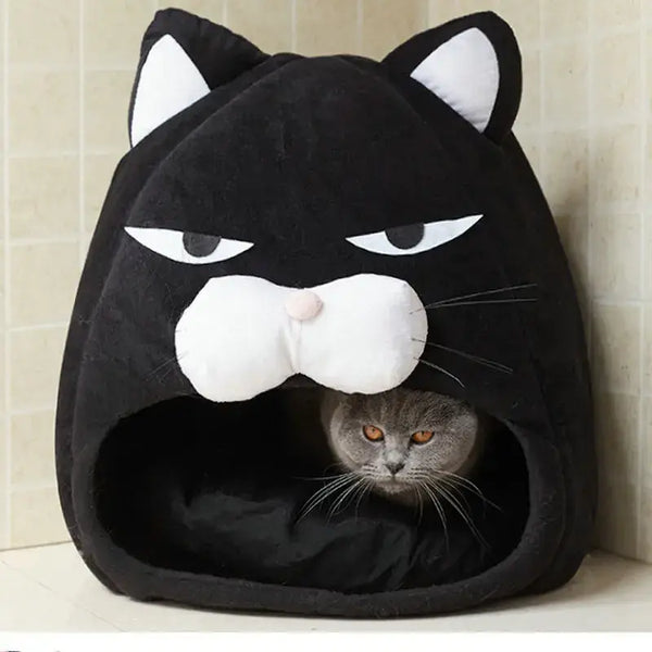Chat dormant dans un couchage pour chat en forme de tête de chat noir