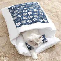 Chat allongé à moitié à l'intérieur d'une couette pour chat, motif bleu et blanc, parfait pour un espace douillet et sécurisé.