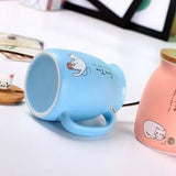 Tasse en céramique bleue allongée à côté de son couvercle en bois tête de chat