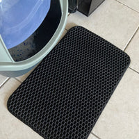 Présentation de notre tapis de litière pour chat noir devant un bac à litière fermé