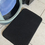 Présentation de notre tapis de litière pour chat noir devant un bac à litière fermé