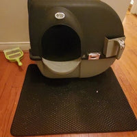 Présentation de notre tapis de litière pour chat devant une maison de toilette